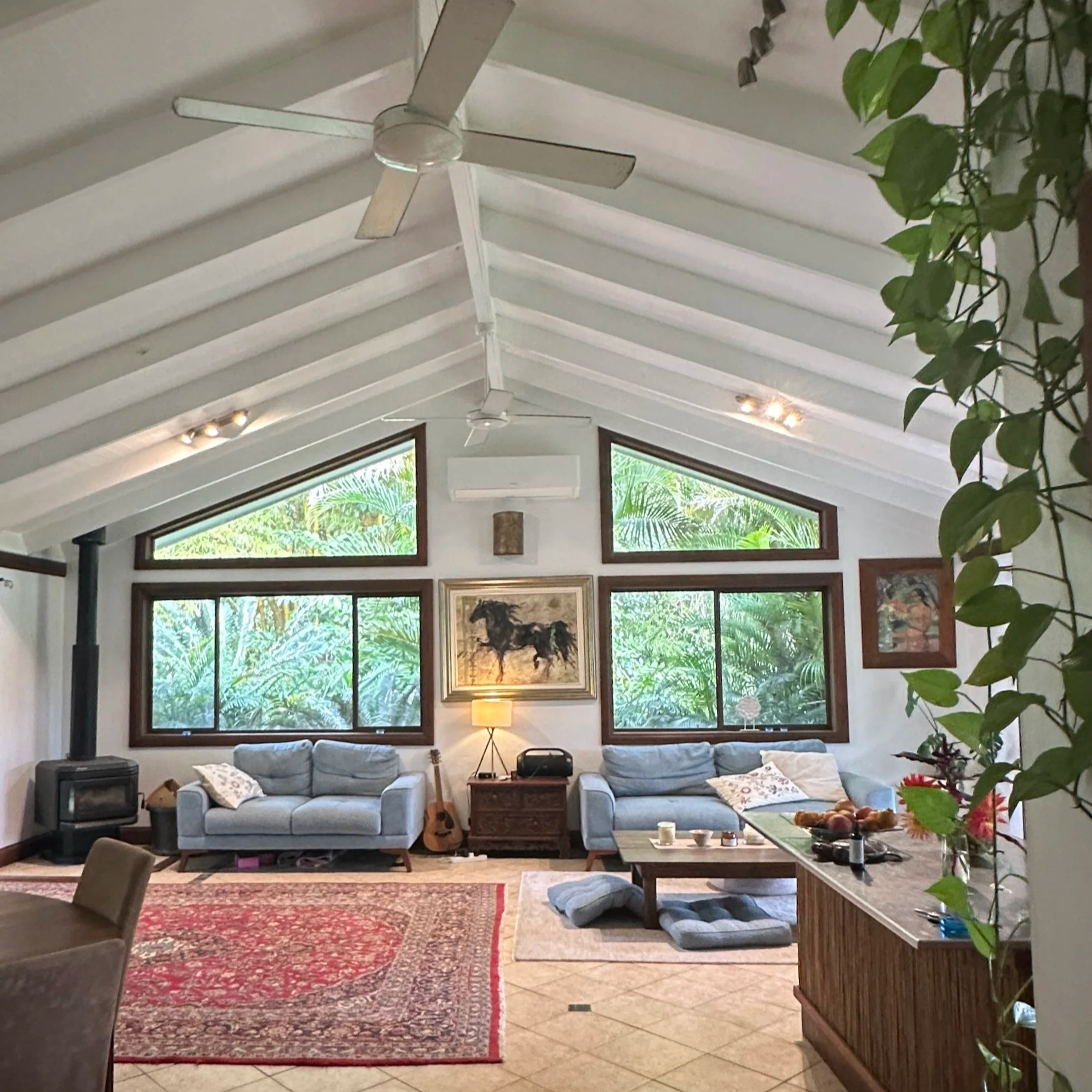 Living room before — dated blue couches, red Persian rug, cluttered and heavy