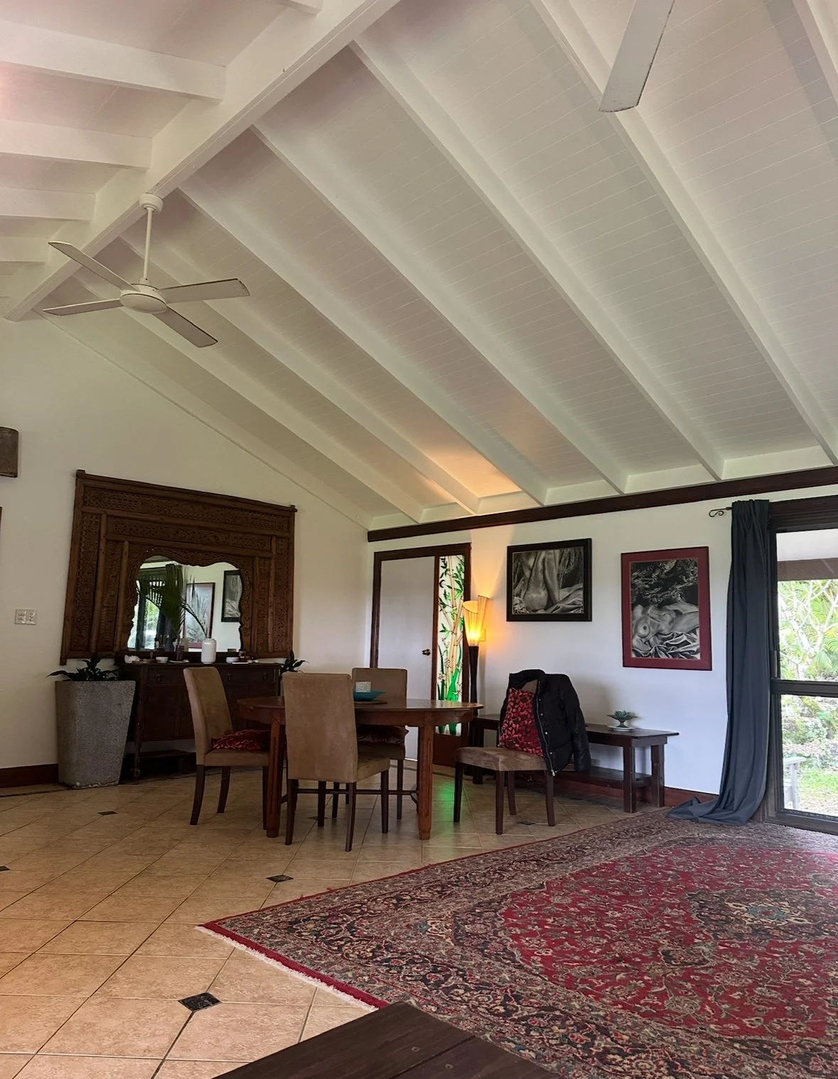 Living and dining before — red Persian rug, dark chairs, heavy mismatched furniture