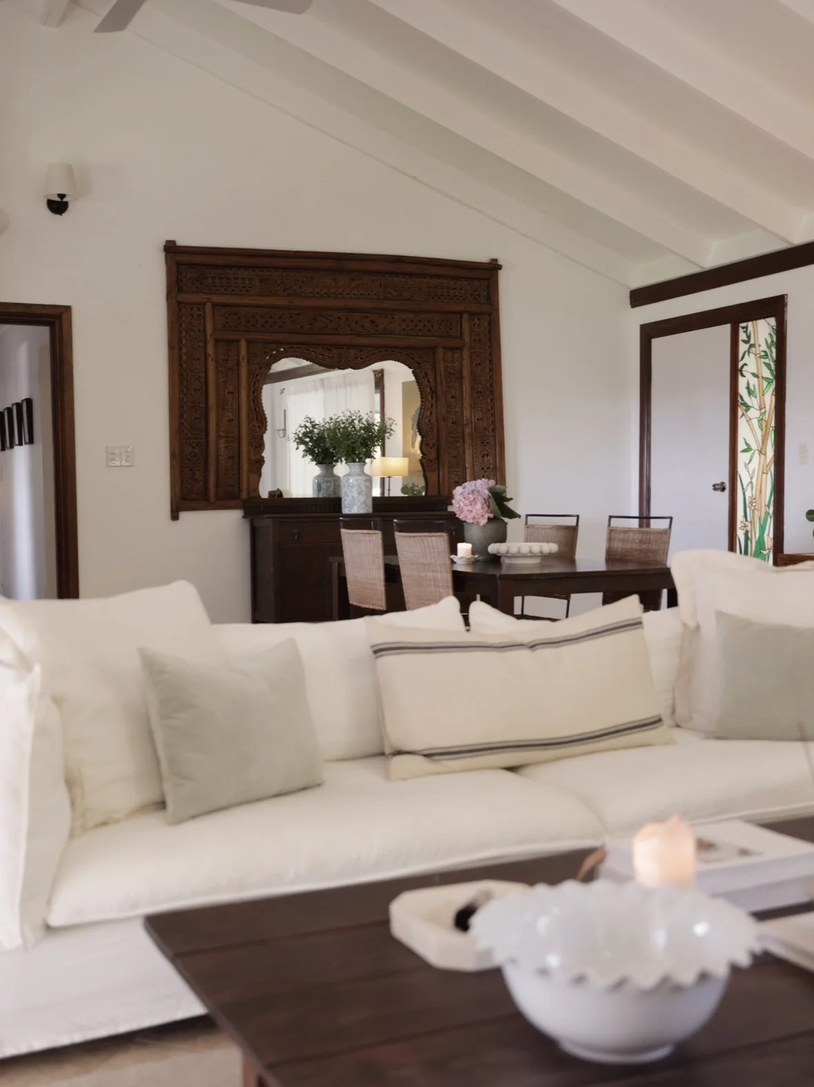 Living and dining after — white sofa, fresh flowers, carved timber mirror as a hero feature