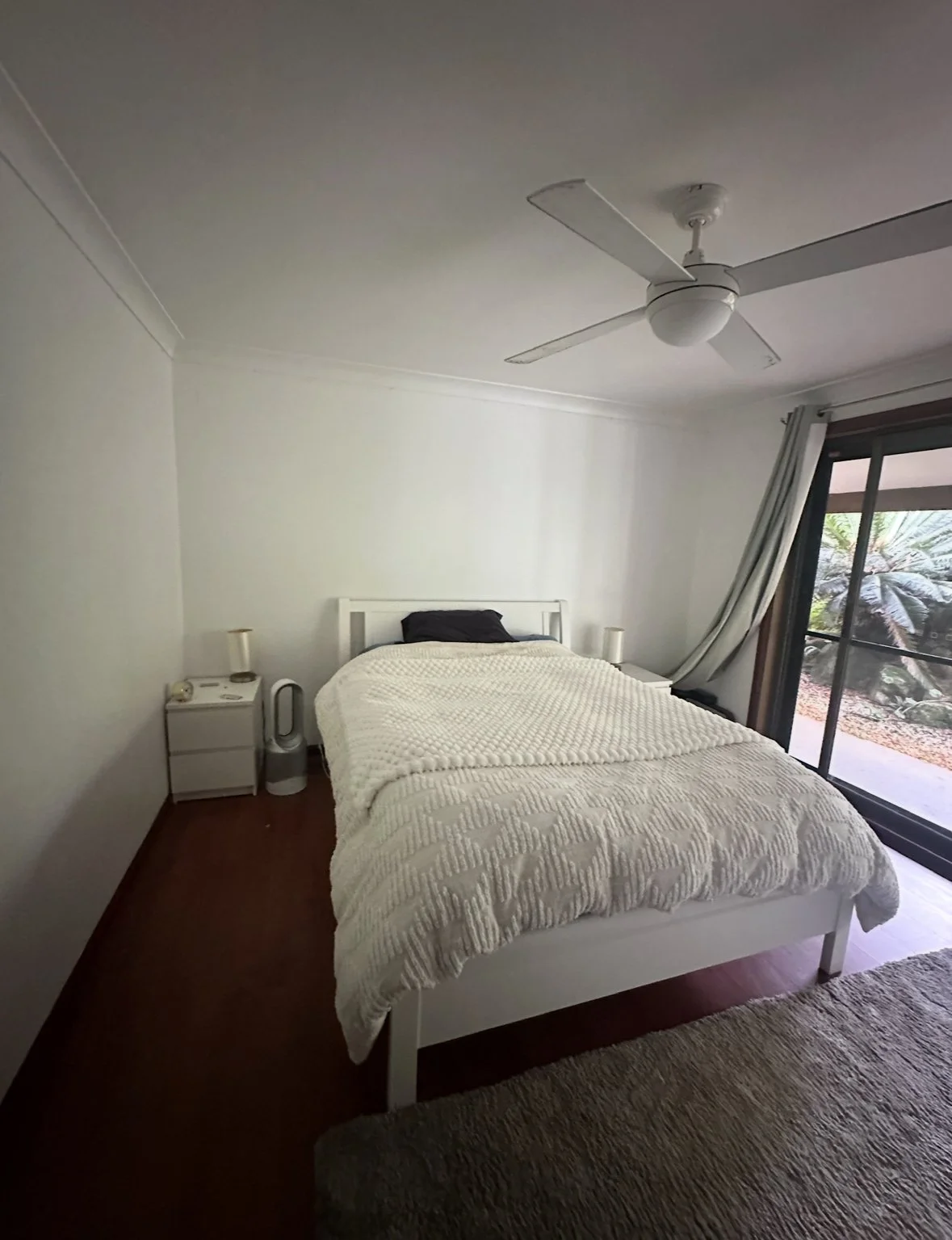 Bedroom before — sparse white bed, bare walls, dark floors, no warmth